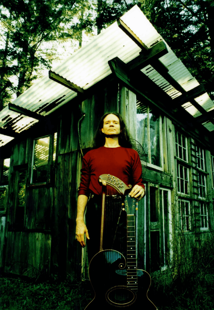 Michael standing in backyard with one of his harp guitars